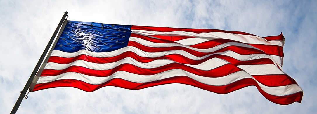 American Flag flying with sky and sun in the background