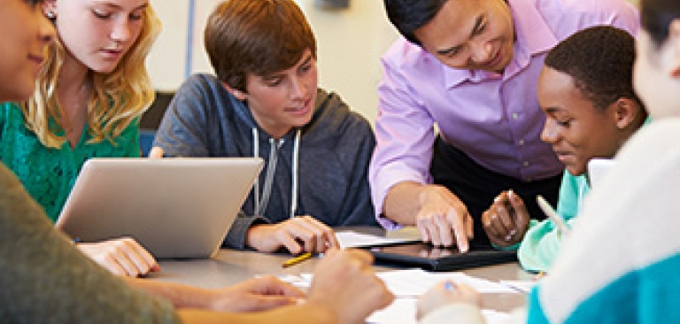 Male teacher working with a group of students in the classroom