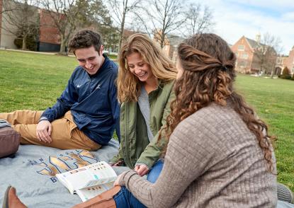 group pf students looking at book on quad