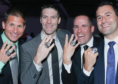 Four John Carroll alumni smile and show their Super Bowl rings. 