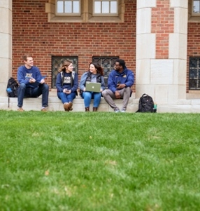 Four JCU students sitting of a curb