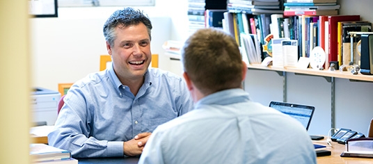Male faculty member offering male student having a conversation